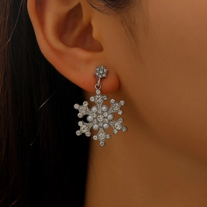 Detail of snowflake earrings with sparkling rhinestones and pearls on model