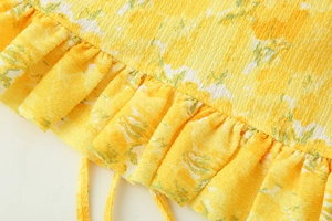 Detail of yellow floral textured fabric showing ruffled edges and pleated material