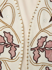 Macro view of V-neckline embroidery with floral patterns and sequins on beige vest