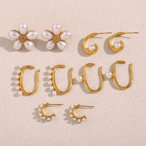 Detailed flat lay of 18K gold plated flower and pearl stud earring set on beige texture