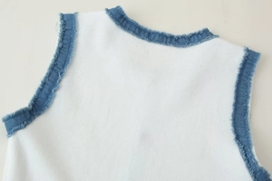 Vue détaillée du tricot côtelé avec bordure effilochée en jean bleu sur un haut blanc