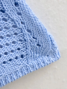 Gros plan sur un tissu en maille bleu clair avec motifs géométriques et fibres douces