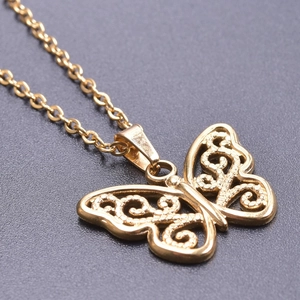 Close-up of golden butterfly pendant with intricate镂空filigree on a sleek metal chain