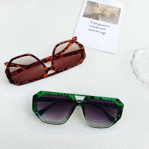 Detailed view of oversized leopard and green sunglasses on a white textured background