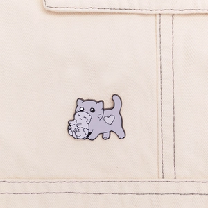 Close-up of lilac enamel cat brooch with white heart on beige canvas background