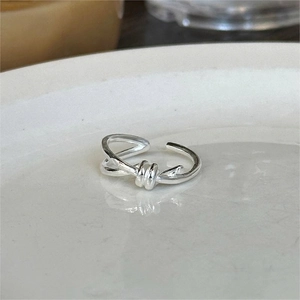 Polished S925 sterling silver knotted ring with adjustable open band on ceramic plate