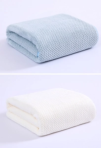 Detailed view of soft waffle weave coral fleece bath towels in light blue and beige colors