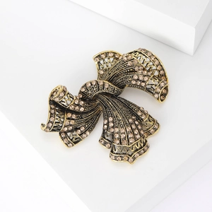 Detail of vintage gold bow brooch featuring champagne rhinestones and woven metal texture