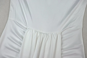 Detailed close-up of white satin fabric with elegant shirred waist stitching and texture