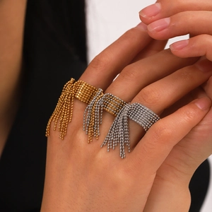 Dettaglio di anelli con nappe di perline in oro e argento indossati da una modella