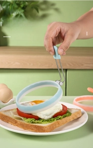 Dettaglio di uno stampo rotondo per uova in silicone con manico isolante su toast
