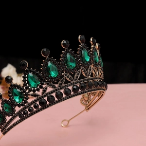 Dettaglio di gemme a goccia color smeraldo e diamanti neri su corona dorata vintage