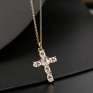 Macro view of a gold cross pendant necklace featuring inlaid clear cubic zirconia stones