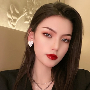 Detail shot of heart-shaped white enamel earrings with golden edges on model