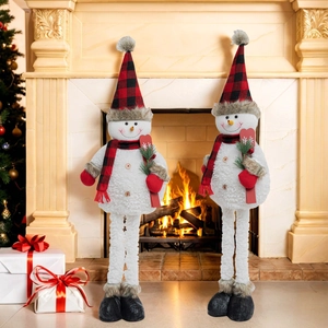 Close-up of plush Christmas snowman figures with red plaid hats by a cozy fireplace