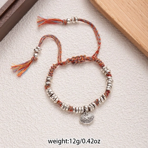 Close-up of colorful braided cotton bracelet with silver beads and longevity lock charm