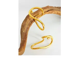 Detail of 18K gold-plated streamlined earrings hanging on a natural wooden branch
