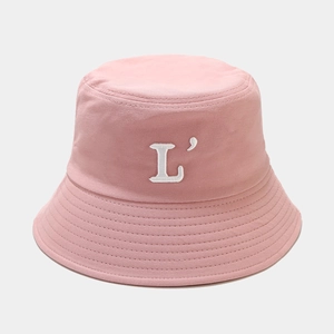 Détail de la broderie lettre L blanche sur un chapeau de soleil rose en coton