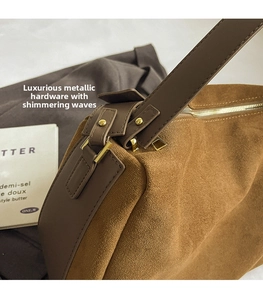 Detail of high-quality gold metal hardware and brown suede texture on a pillow bag