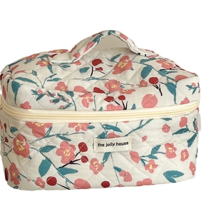Quilted floral cosmetic bag with cherry patterns and top handle for travel storage