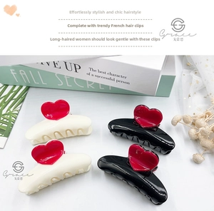 Detail of black and cream hair claws with red heart accents on decorative books