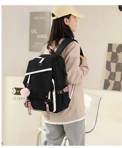 Detail of black nylon backpack with pink sport straps and a cute plush ball charm