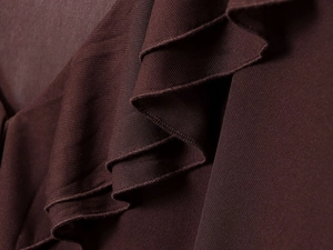 Detailed macro view of dark coffee knit fabric with elegant layered ruffle pleated design