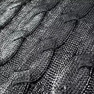 Vue détaillée de la maille torsadée noire avec des textures de fils métalliques brillants