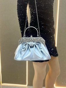 Detail of silver-blue satin evening bag with pleated texture and rhinestone handles