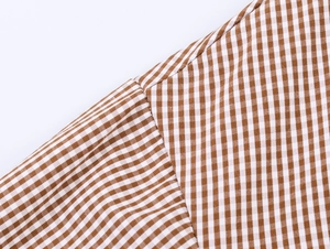 Nahaufnahme von braun-weißem Karo-Hemdstoff mit detaillierter Textur und Nahtdetails