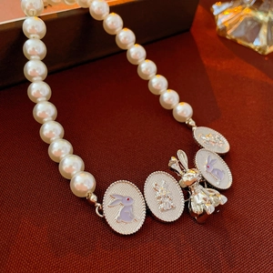 Collana choker vintage di perle con pendenti a coniglio in argento su fondo rosso