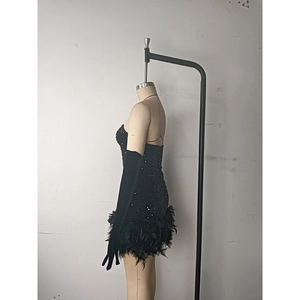 Detailed view of sequined party dress with feather hem and matching long gloves
