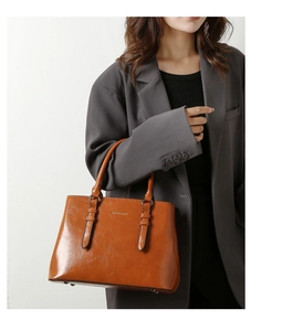 Detail of caramel leather tote bag showing fine texture and protective metal base rivets