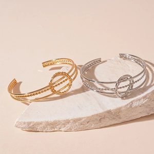 Three-layer geometric open cuff bracelet in gold and silver finish on white stone