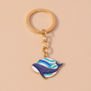 Détail d'un porte-clés baleine avec rayures bleues pailletées et anneau en métal doré