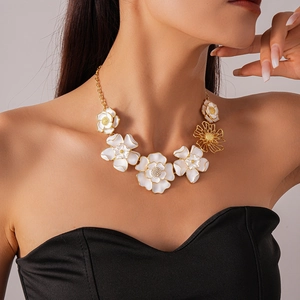 Close-up of model wearing gold chain necklace with white 3D floral petals and rhinestones