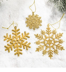 Close-up of three golden glitter snowflake ornaments with strings for Christmas trees