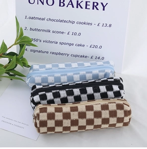 Three stacked knit checkerboard pencil cases in blue, black, and brown patterns