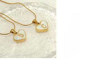 Close-up of 18K gold-plated stainless steel heart pendant with white shell and letter detail