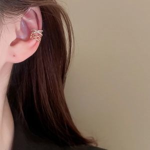 Detailed close-up of a layered gold ear cuff with zircon crisscross design on a model