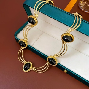 Macro detail of vintage gold twist chain necklace with black oval stones in a jewelry box