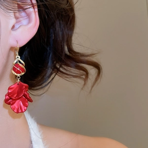 Close-up of red petal tassel earrings with gold metal accents worn by a person
