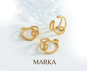 Macro shot of three 18K gold plated titanium steel wavy rings on a textured surface