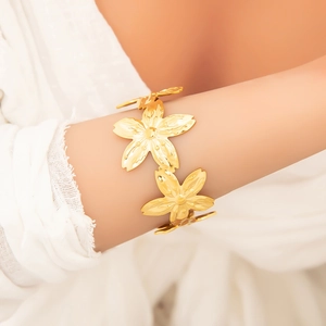 Elegant gold flower cuff bracelet in titanium steel shown on woman's wrist