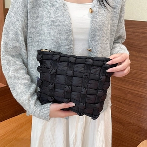 Detail of black puffy quilted handbag with bubble knots and golden zipper closure