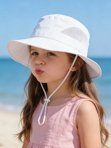 Detailed view of kids white sun hat with breathable mesh and adjustable chin strap on beach