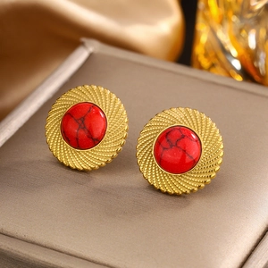 Vue macro de boucles d'oreilles vintage dorées avec pierre marbrée rouge sur support