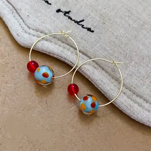 Bohemian gold hoop earrings featuring red transparent and blue polka dot resin beads