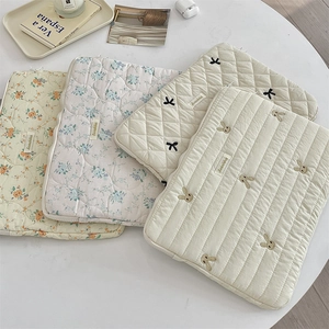 Detailed close-up of quilted cotton laptop sleeves with cute floral and rabbit embroidery