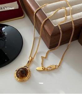 Detailed close-up of a vintage oval smoky quartz pendant on a golden chain with velvet stand